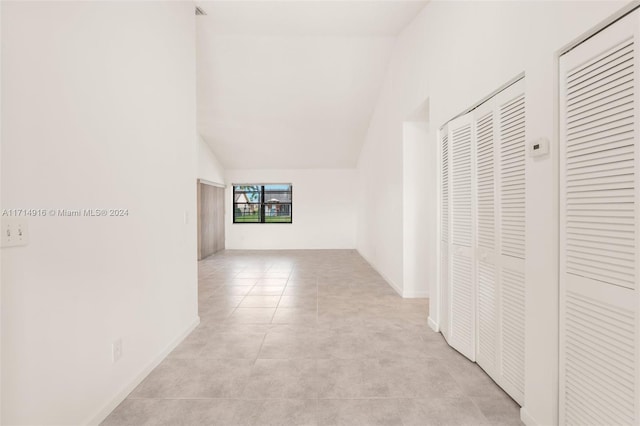 corridor featuring light tile patterned floors and lofted ceiling