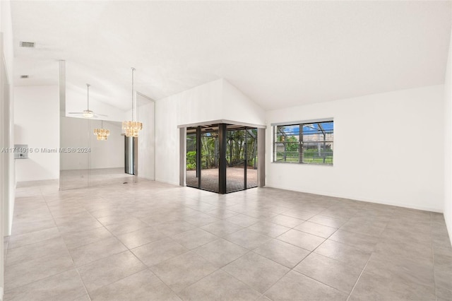 spare room featuring ceiling fan with notable chandelier, vaulted ceiling, and light tile patterned flooring