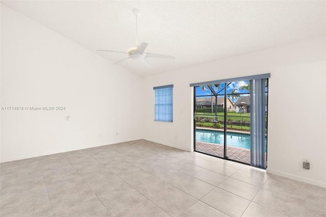 tiled empty room featuring ceiling fan, lofted ceiling, and a textured ceiling