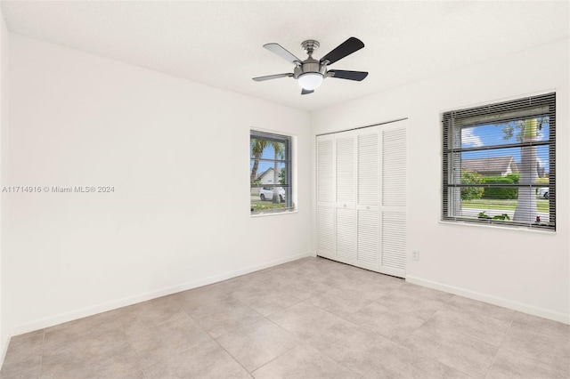 unfurnished bedroom with ceiling fan, light tile patterned flooring, and a closet