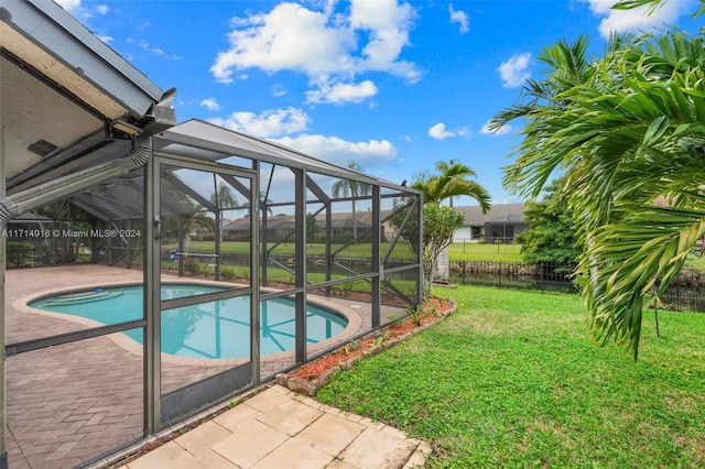 view of pool with a lawn, glass enclosure, and a patio area