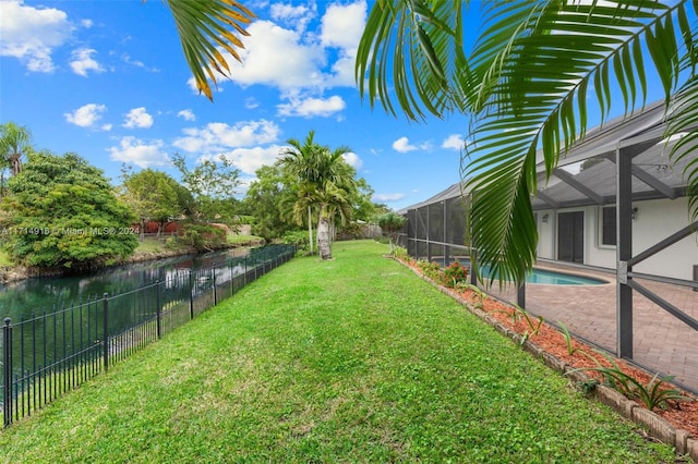 view of yard with a lanai, a water view, and a fenced in pool