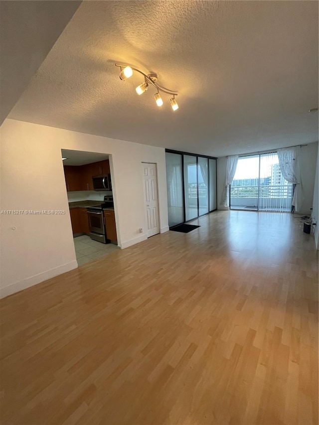 unfurnished living room featuring light hardwood / wood-style flooring, a textured ceiling, and a wall of windows