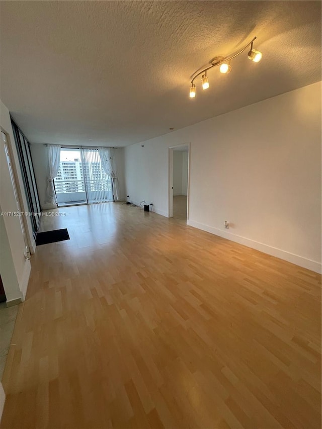 unfurnished room with light wood-type flooring and a textured ceiling