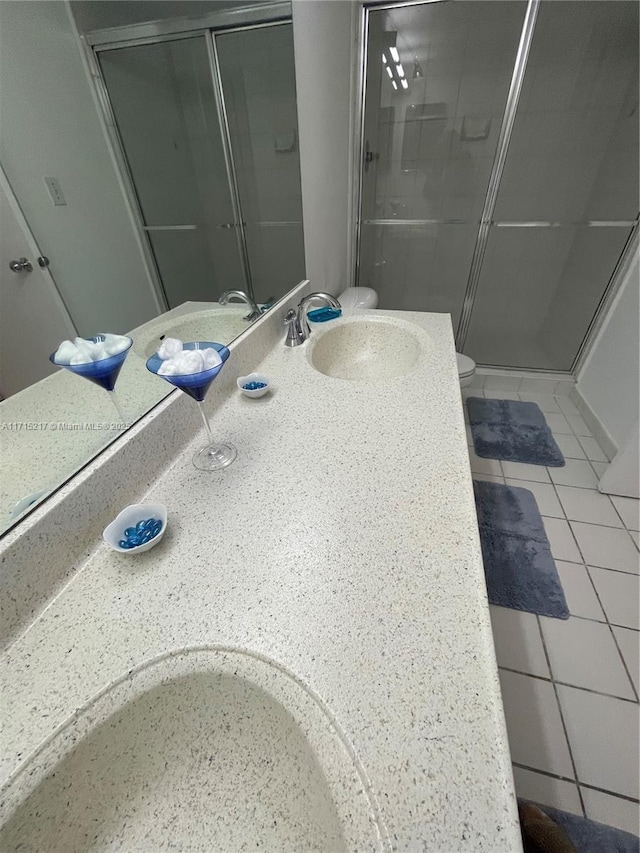 bathroom featuring tile patterned floors, vanity, toilet, and a shower with door