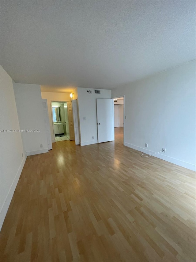 unfurnished living room featuring a textured ceiling and light hardwood / wood-style flooring