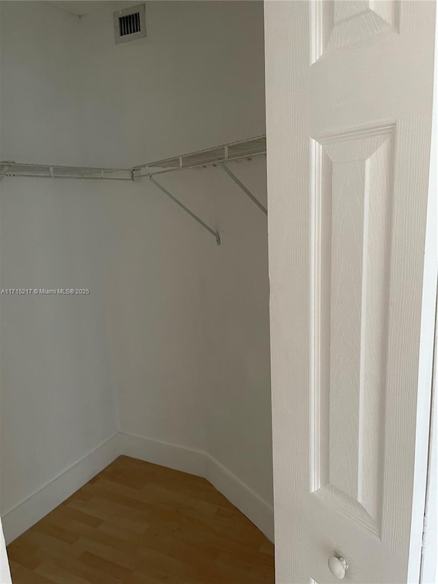 walk in closet with hardwood / wood-style flooring