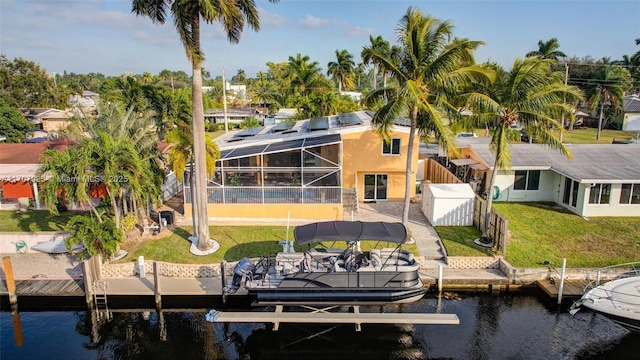 view of dock with a lanai, a yard, and a water view