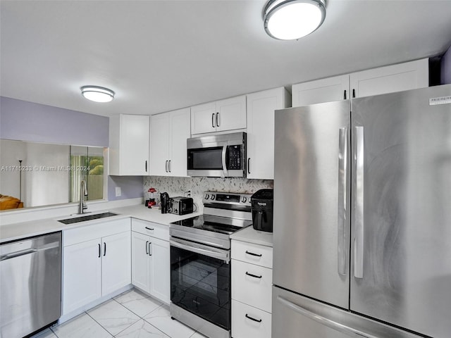 kitchen featuring backsplash, white cabinetry, sink, and stainless steel appliances