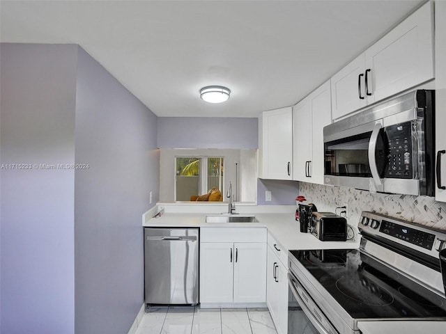 kitchen with appliances with stainless steel finishes, white cabinetry, and sink