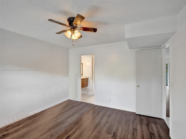 empty room featuring ceiling fan, dark wood-type flooring, and a textured ceiling