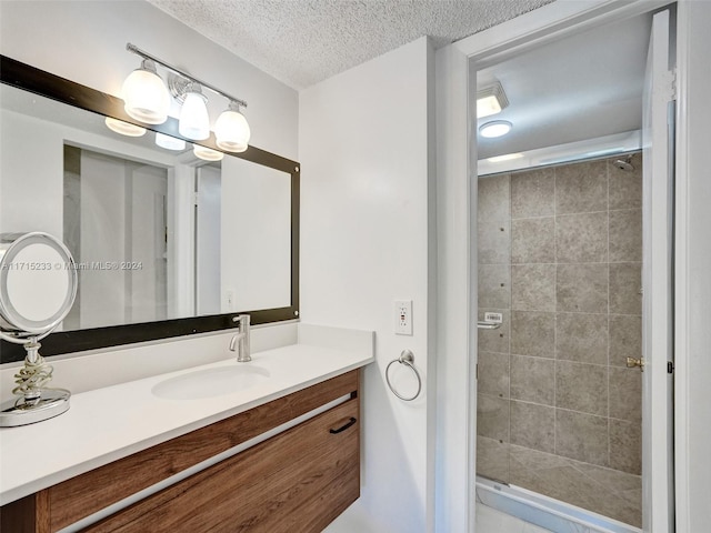 bathroom featuring a tile shower, vanity, and a textured ceiling