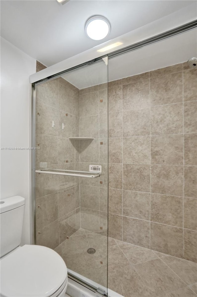 bathroom with toilet and a shower with door