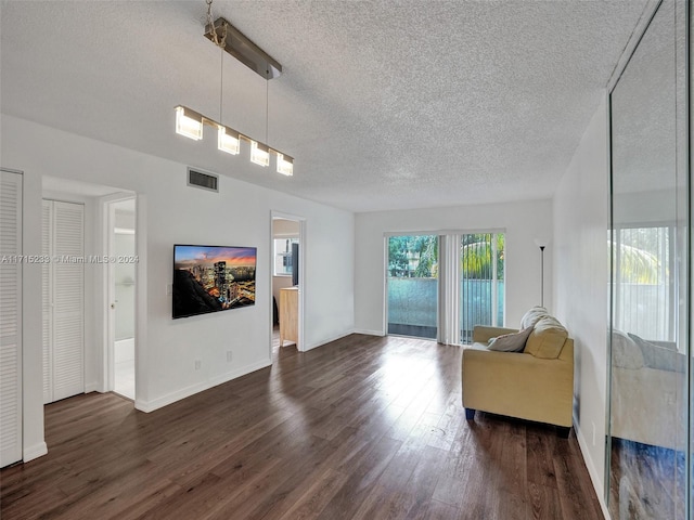 living room with a textured ceiling and dark wood-type flooring