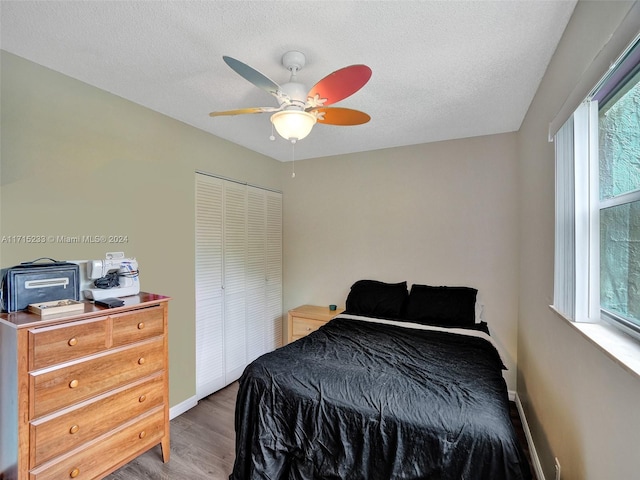 bedroom with ceiling fan, a closet, wood-type flooring, and a textured ceiling