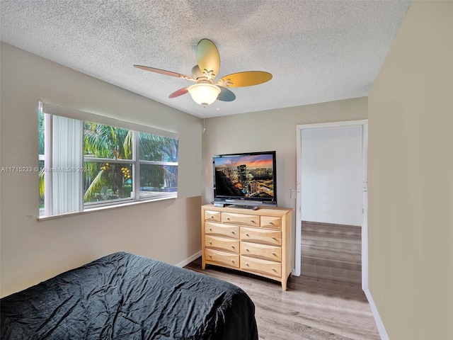 bedroom with ceiling fan, light hardwood / wood-style floors, and a textured ceiling