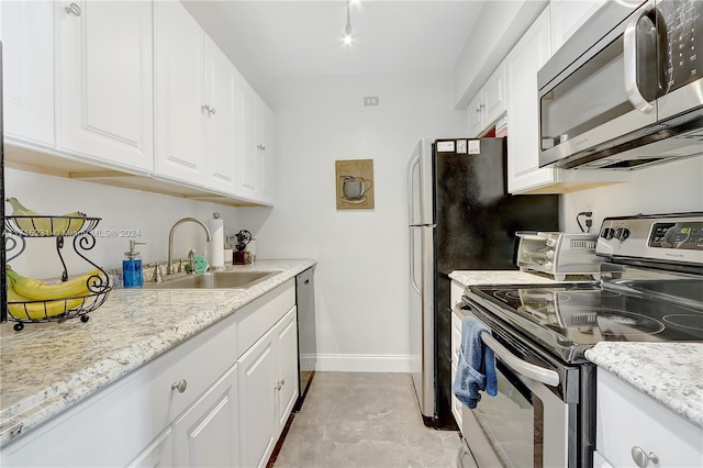 kitchen with white cabinets, sink, light stone countertops, and stainless steel appliances