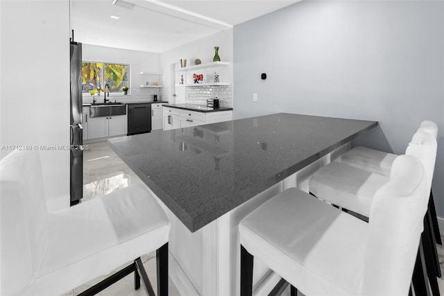 kitchen featuring a breakfast bar area, dishwasher, white cabinets, and sink