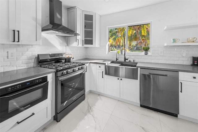 kitchen featuring backsplash, stainless steel appliances, sink, wall chimney range hood, and white cabinets