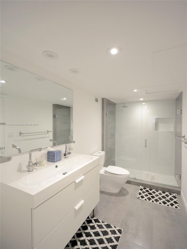 bathroom with a shower with door, vanity, and toilet