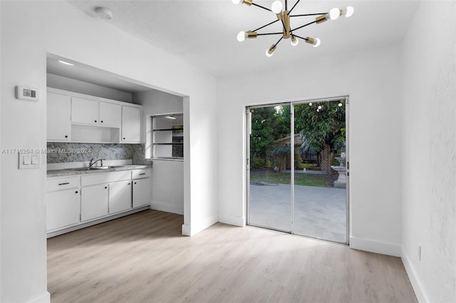 kitchen featuring white cabinets, sink, decorative backsplash, light wood-type flooring, and a chandelier