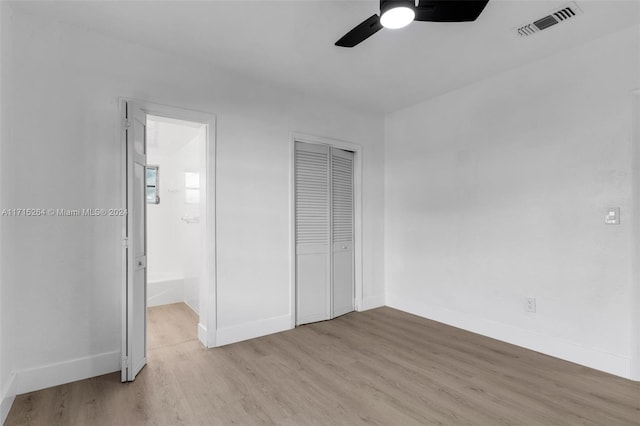 unfurnished bedroom with connected bathroom, a closet, light hardwood / wood-style flooring, and ceiling fan