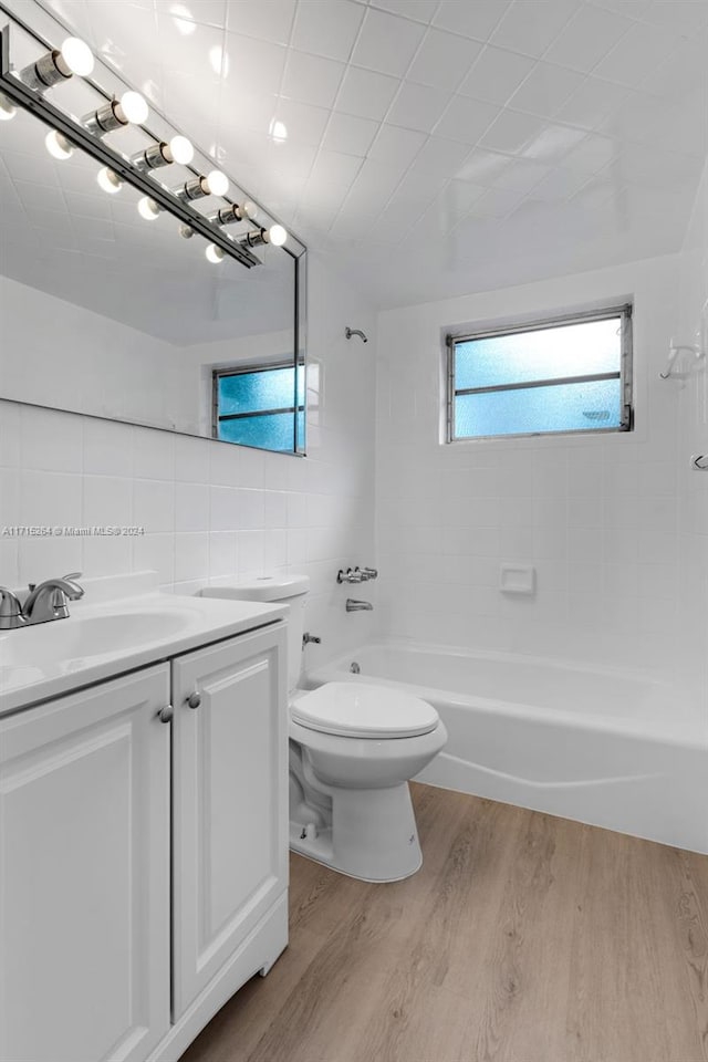 full bathroom with hardwood / wood-style floors, vanity, backsplash, tiled shower / bath, and tile walls