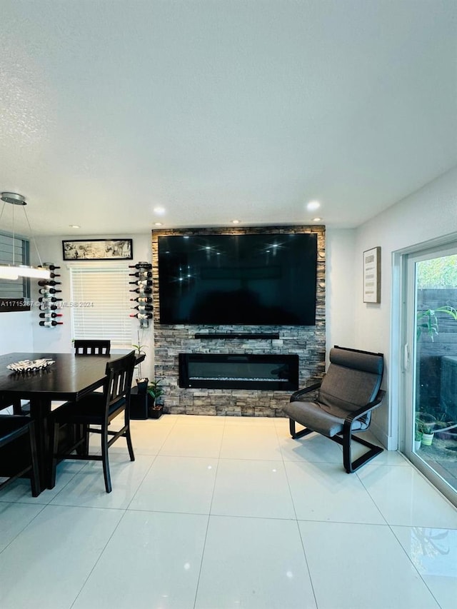 tiled living room featuring a stone fireplace and a textured ceiling