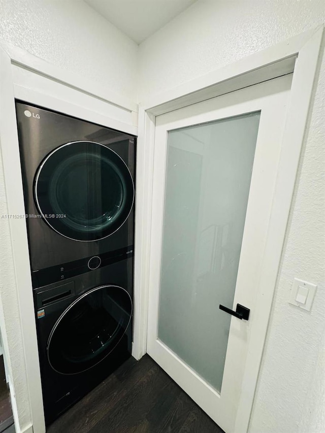 laundry room with stacked washing maching and dryer and dark wood-type flooring