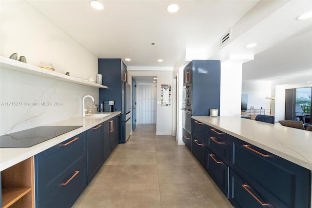 kitchen with light stone countertops, sink, blue cabinets, and stainless steel appliances