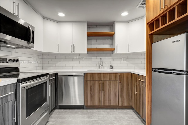 kitchen featuring decorative backsplash, stainless steel appliances, white cabinetry, and sink