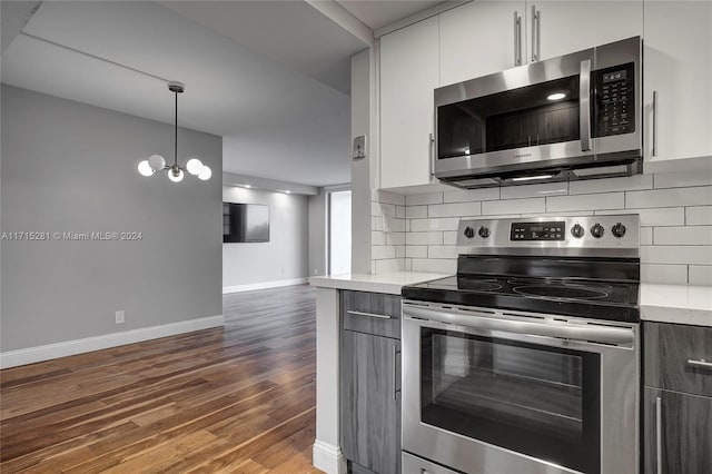 kitchen featuring a notable chandelier, dark wood-type flooring, white cabinets, appliances with stainless steel finishes, and decorative light fixtures