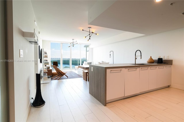 kitchen featuring kitchen peninsula, sink, expansive windows, and light hardwood / wood-style flooring