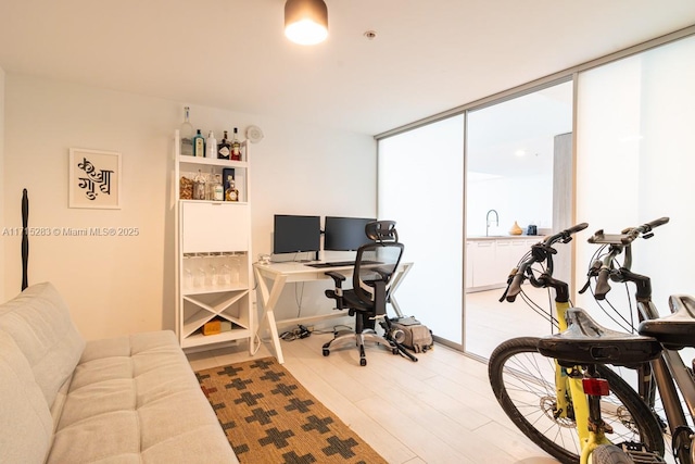 office with floor to ceiling windows and light hardwood / wood-style flooring