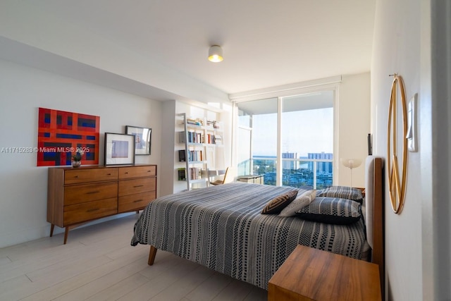 bedroom with light hardwood / wood-style floors and a wall of windows