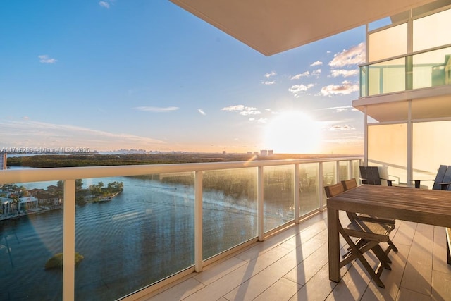 balcony at dusk featuring a water view