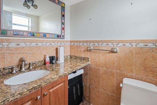 bathroom featuring vanity, toilet, and tile walls