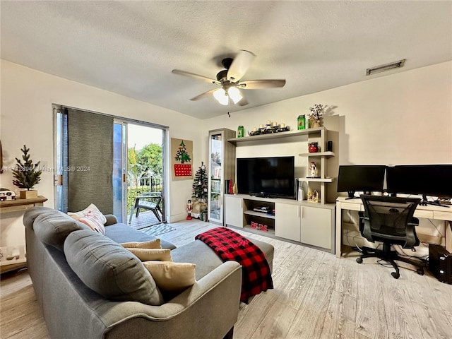 living room featuring ceiling fan, a textured ceiling, and light wood-type flooring