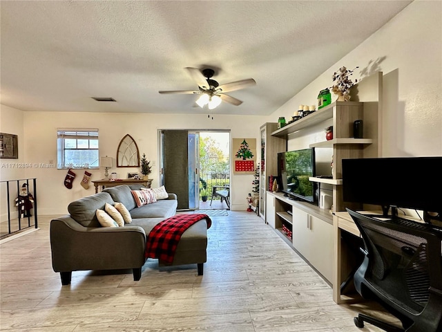 living room with plenty of natural light, light hardwood / wood-style floors, a textured ceiling, and ceiling fan