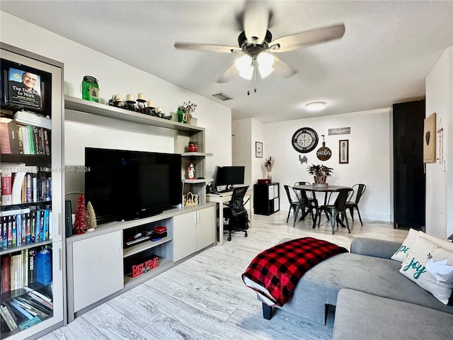 living room with a textured ceiling, light hardwood / wood-style floors, and ceiling fan