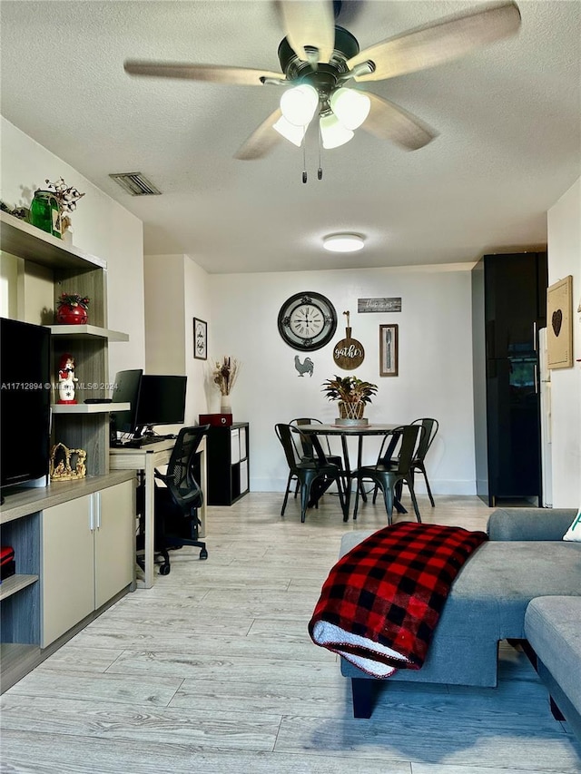 home office with ceiling fan, light hardwood / wood-style flooring, and a textured ceiling