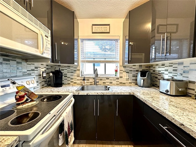 kitchen with tasteful backsplash, light stone countertops, sink, and white appliances