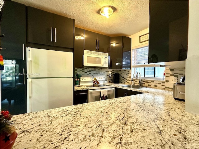 kitchen with white appliances, backsplash, sink, a textured ceiling, and dark brown cabinets