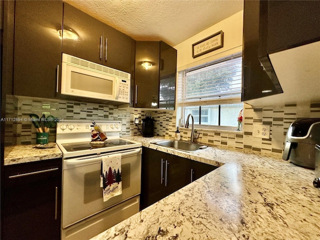 kitchen with dark brown cabinetry, decorative backsplash, sink, and white appliances