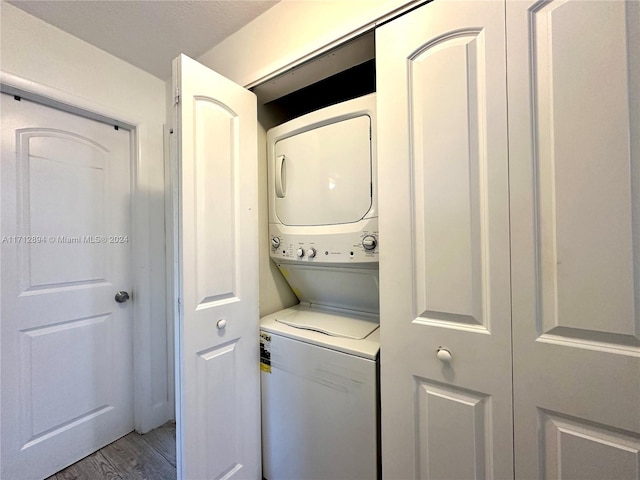 laundry room featuring stacked washer / drying machine and hardwood / wood-style flooring