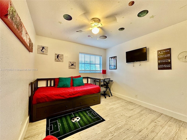 bedroom with ceiling fan, a textured ceiling, and light wood-type flooring