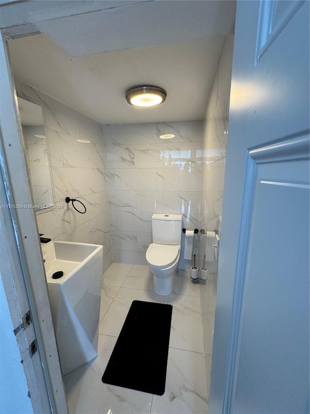 bathroom featuring tile walls and toilet