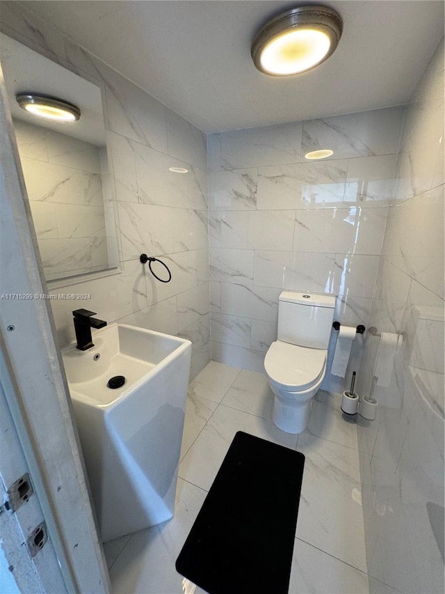 bathroom with toilet, tile walls, and sink