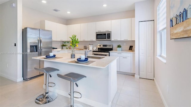 kitchen with sink, stainless steel appliances, a breakfast bar area, a kitchen island with sink, and white cabinets