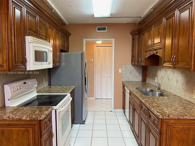 kitchen with light tile patterned floors, white appliances, backsplash, and sink